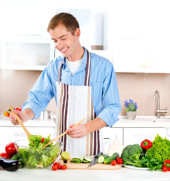 Young Man Cooking. Healthy food. Vegetable Salad