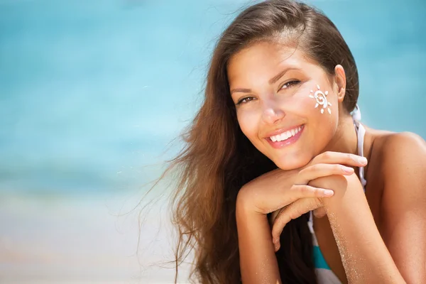 Beautiful happy Girl applying Sun Tan Cream on her Face