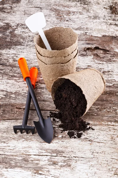 Garden tools (shovel, rake, peat pots ) on old wooden background