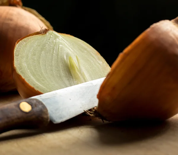 Onion and knife on wooden board