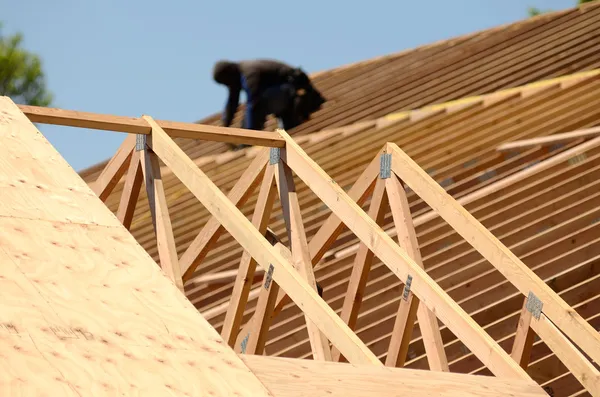A roofing contractor installing rafters at a commercial residential development.