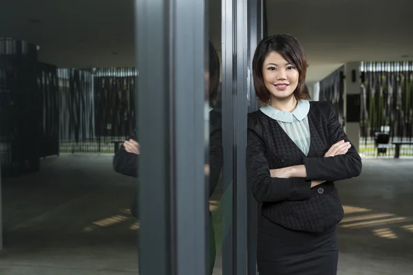 Happy Chinese Business woman standing by window.