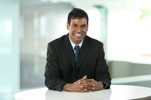 Indian business man sitting at a desk.
