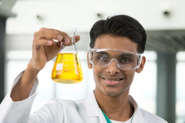Male scientist looking at beaker of liquid