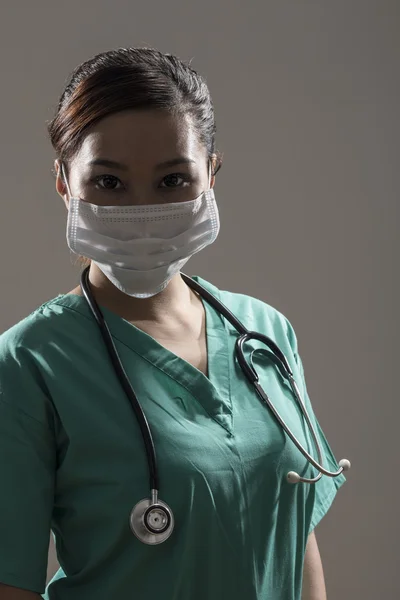 Chinese doctor wearing a face mask, green scrubs and stethoscope