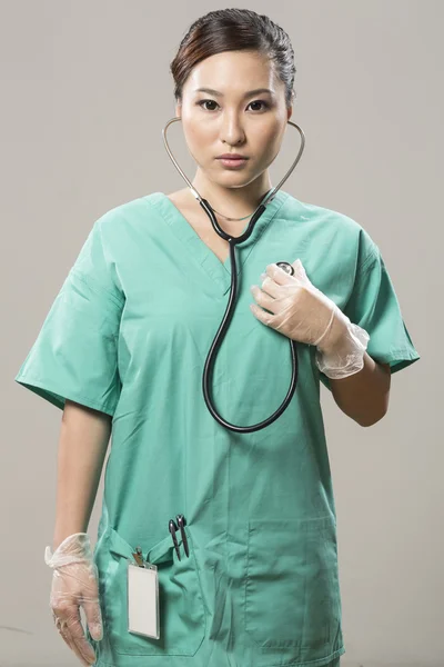 Chinese Doctor in scrubs holding stethoscope to chest