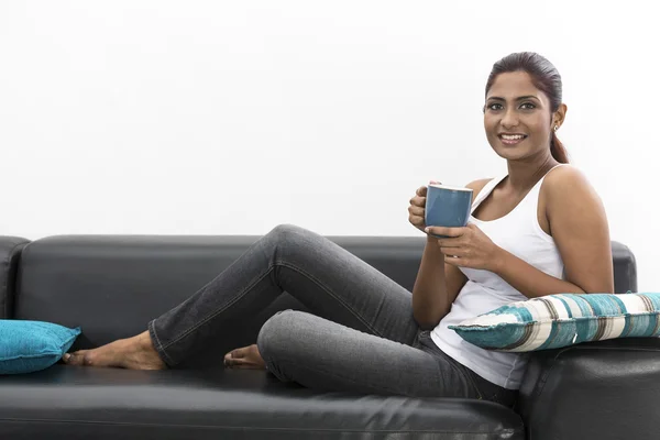 Indian woman relaxing on the couch a coffee