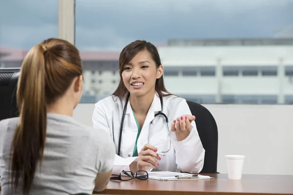 Asian doctor talking with female patient