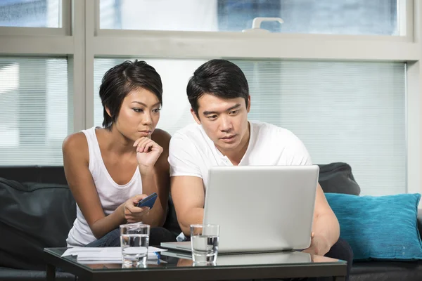 Young Chinese couple using a laptop at home