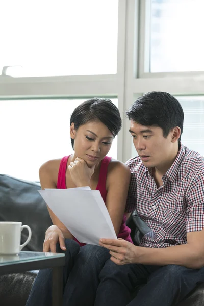 Serious Asian couple reading a financial bill