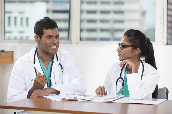 Two Indian doctors sitting working at a desk together