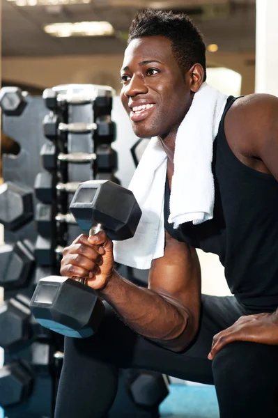 Young gym instructor toning his biceps