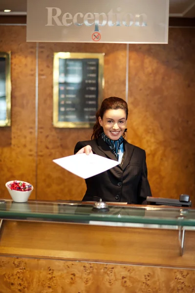 Female receptionist handing over check-out papers