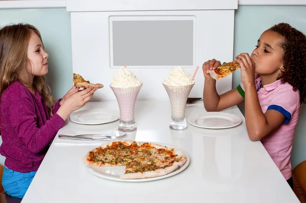 Little girls enjoying pizza in a restaurant