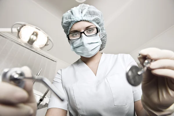 Female dentist working with mirror and tool