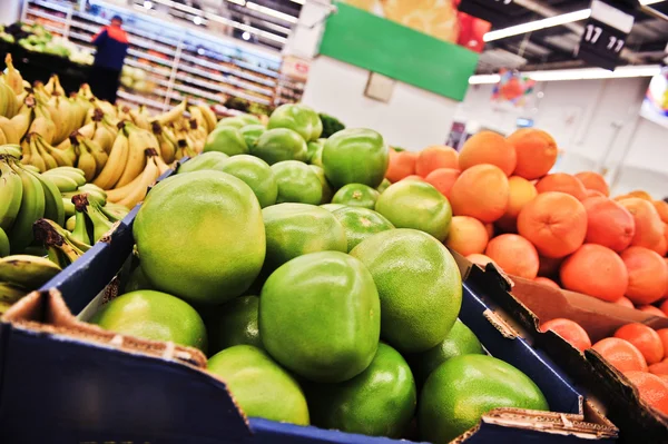 Green pomelos in boxes in supermarket