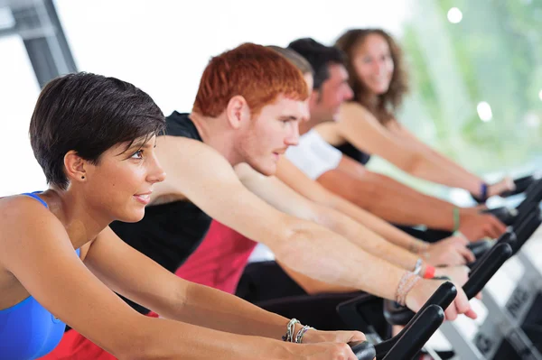 Group of five in the gym, exercising their legs doing car