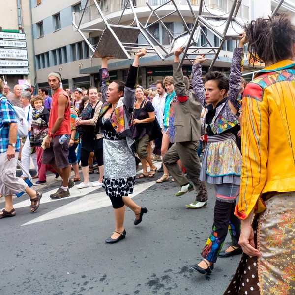 Parade of street performers carrying bar stools.