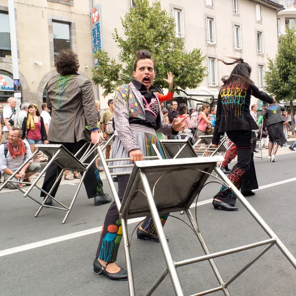 Street performer carrying bar stools.