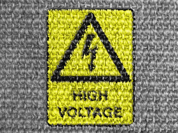 High voltage sign drawn at grey fabric