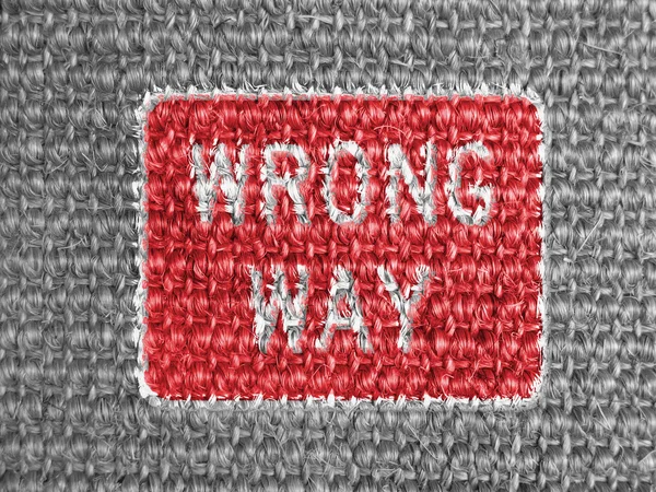 Wrong way road sign painted on grey fabric
