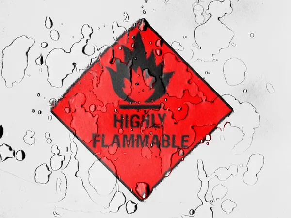 Highly flammable sign drawn on covered with water drops