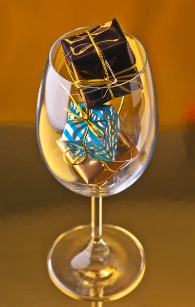 Glasses with gifts and Christmas decorations, on gold base