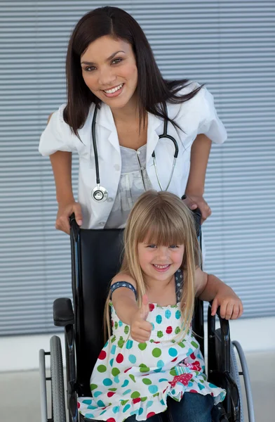 Young female doctor and Smiling girl on a wheelchair with thumb