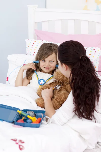 Mother and sick daughter playing with a stethoscope