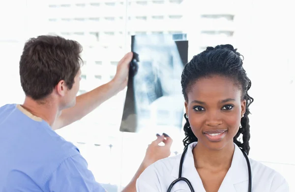 Doctor looking at a of X-ray while his colleague is posing