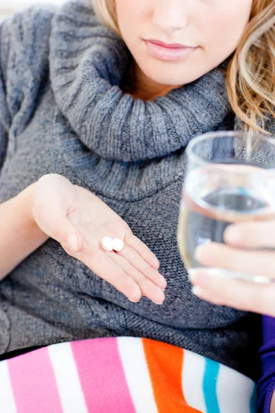 Close-up of an ill woman holding pills and water