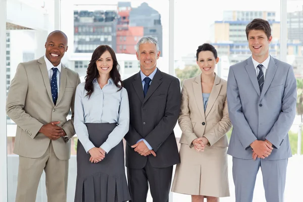 Smiling business team standing upright side by side with their h