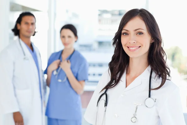 Young nurse standing in front of two colleagues