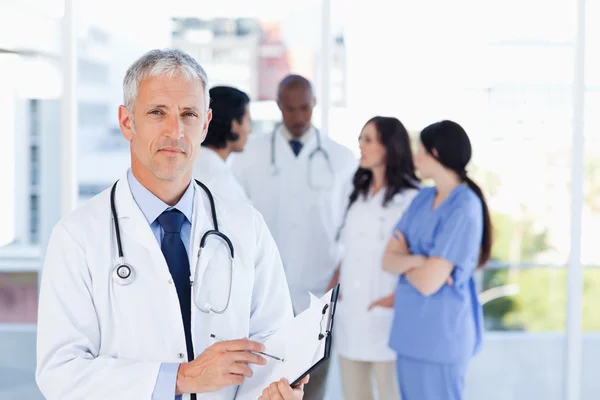 Mature doctor pointing at something on his clipboard