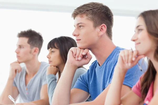 Side view of four students with hands on their chins thinking