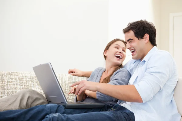 Couple laughing while typing on a computer