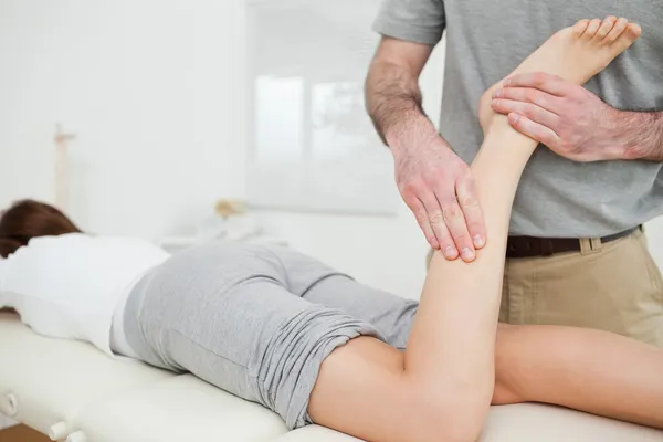 Woman lying while a doctor is examining her leg