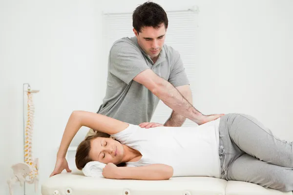 Osteopath crossing his arms while massaging a woman