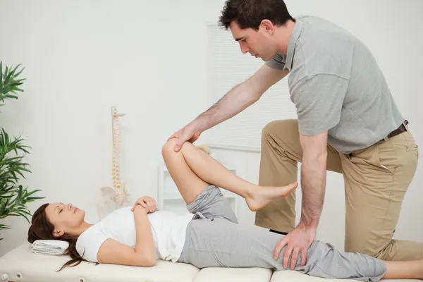 Serious doctor stretching the leg of a woman