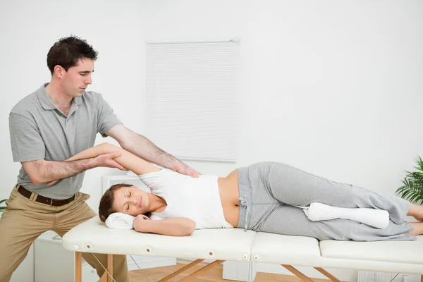 Chiropractor stretching the arm of his patient while holding it