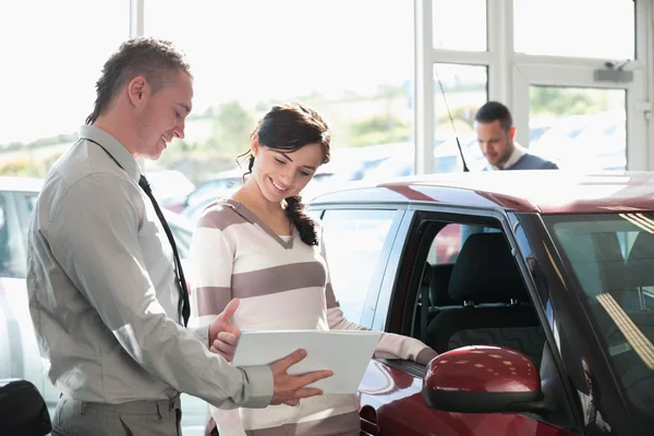 Smiling woman chatting with a car dealer