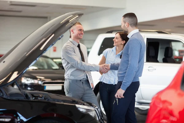 Man shaking hand of a car dealer in front of a car