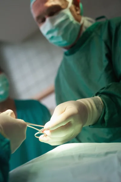 Surgeon taking scissors from a gloved hand