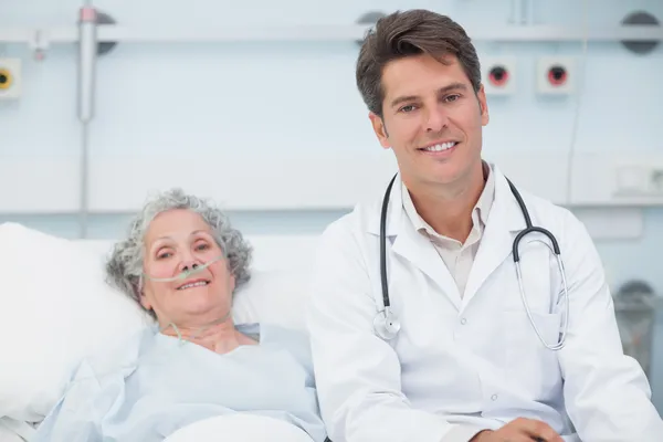 Doctor sitting on the bed next to a patient