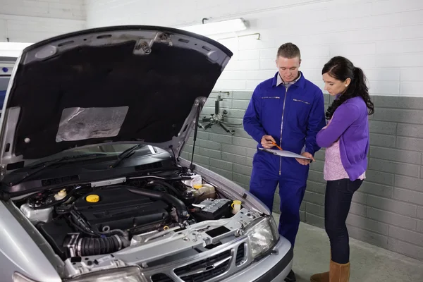 Mechanic holding a clipboard next to a woman