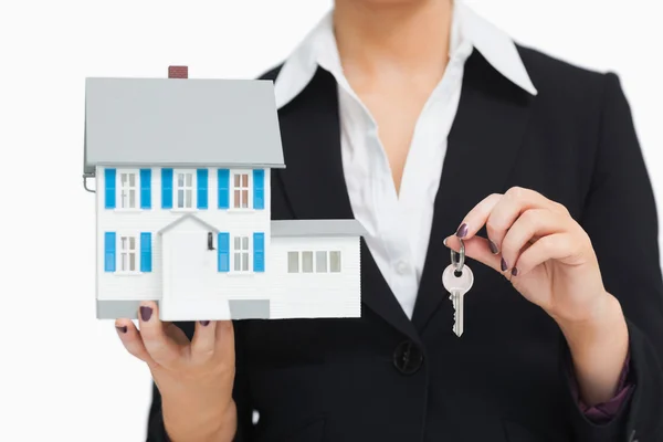 Businesswoman in suit holding a model house and key