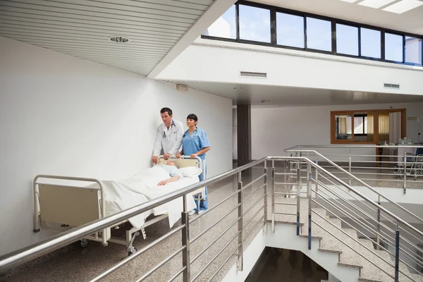 Doctor and nurse pushing patient in bed