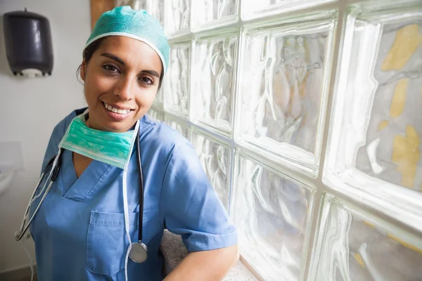 Happy nurse leans against glass wall