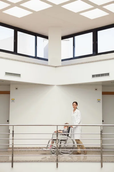 Doctor pushing child with neck brace in wheelchair