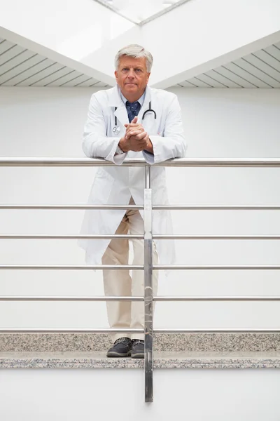 Doctor leaning on rail in hospital corridor